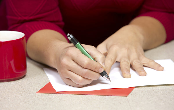 person writing on a card with a pen